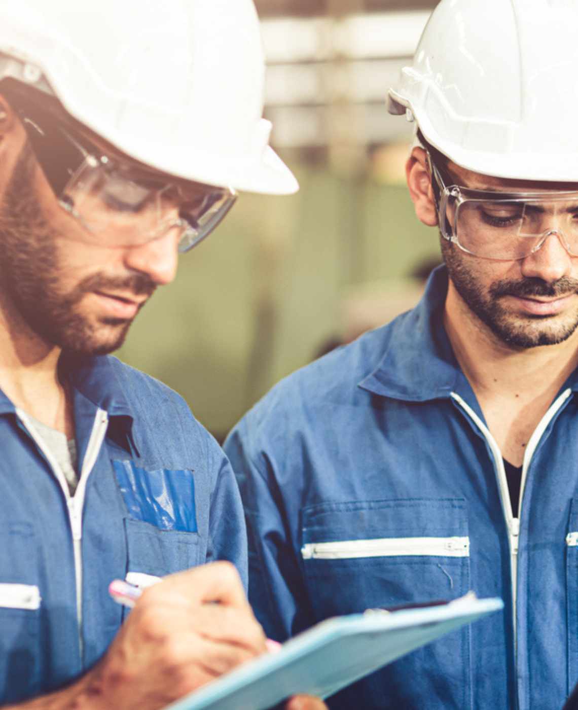 Two facility workers wearing safety gear conducting a facility inspection.